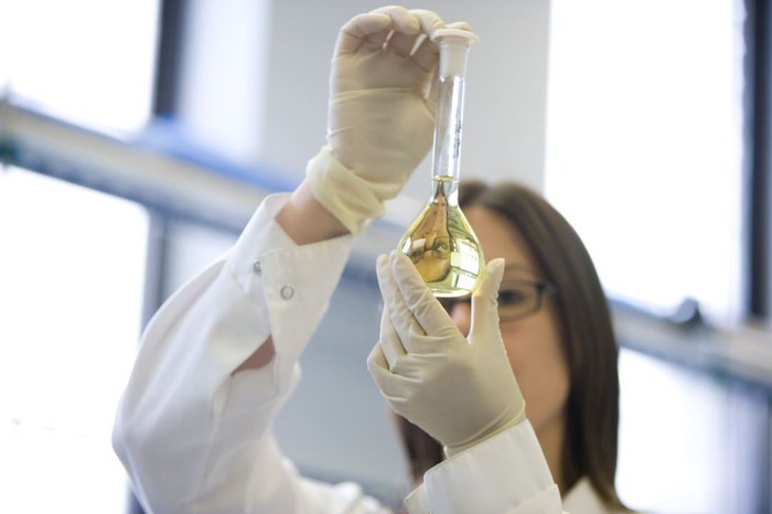 A GW Pharmaceuticals lab researcher examining cannabinoid-rich liquid in a flask.